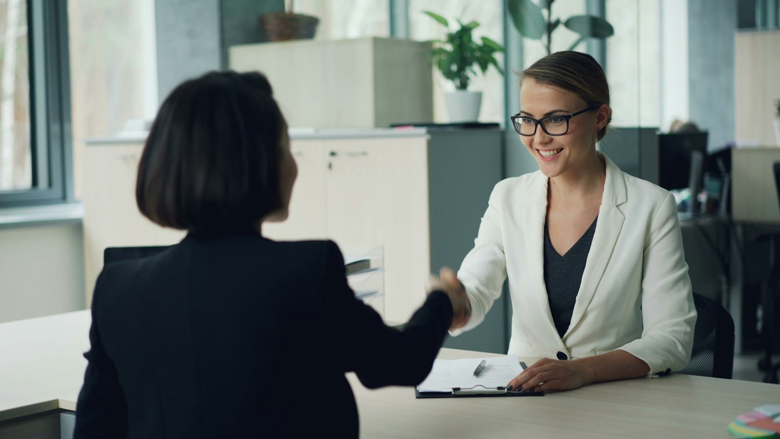 Two professionals shaking hands across a desk